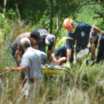 rescuers bring an injured man up the hill